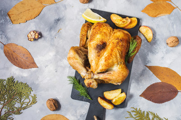 Roasted turkey with apples on a rustic concrete table decorated with walnut and autumn leaf. Flat...