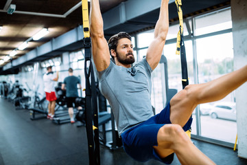 Young handsome man doing exercises in gym