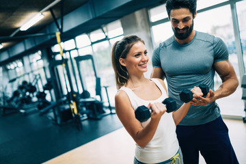 Young beautiful woman doing exercises with personal trainer