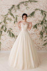 Obraz premium beautiful bride in a white fluffy dress, wedding theme, freedom. Full-lenght portrait on rustic wall background