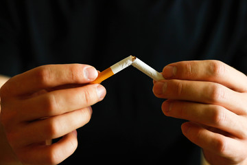 A man holds a broken cigarette in his hand. Close up. Isolated background