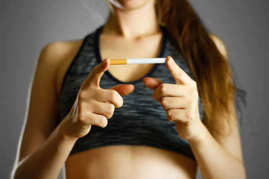 Sports girl holding a cigarette. Close up. Isolated background