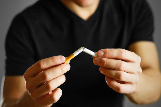 A man holds a broken cigarette in his hand. Close up. Isolated background