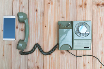 Retro rotary telephone or vintage phone with cable and new cell phone or smart phone on wood table,...