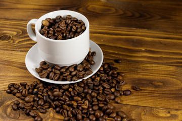 Coffee beans in white cup on wooden table