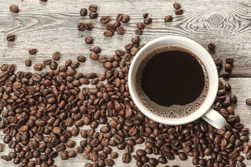 Cup of coffee and beans on wooden background