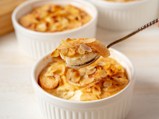 Cheesecake on white wooden table in kitchen. Delicate curd dessert with apples, almond flakes and cinnamon, side view