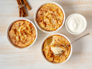 Cheesecake on white wooden table in kitchen. Delicate curd dessert with apples, almond flakes and cinnamon, top view, above