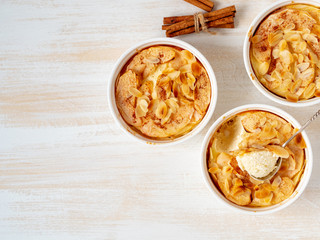 Cheesecake on white wooden table in kitchen. Delicate curd dessert with apples, almond flakes and cinnamon, top view, above