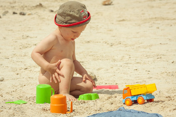 Cute baby boy playing with beach toys on tropical beach