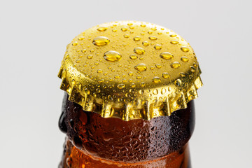 Bottle with soft drinks or alcohol in the ice. On gold caps and a bottle neck are drops of dew....