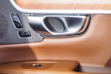 Obraz premium Car light brown leather and interior details of door handle with windows power seat controls and adjustments. Luxury car inside. Interior of prestige modern car.