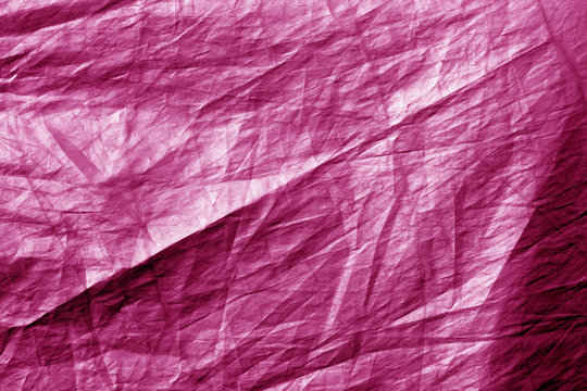 Crumpled plastic textile texture in pink color.