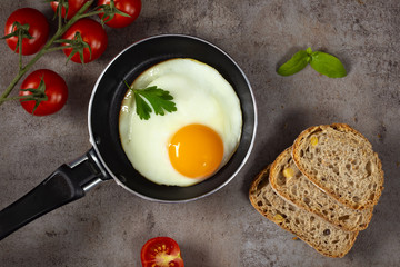 One egg in a little pan with cherry tomatoes and three slice of bread