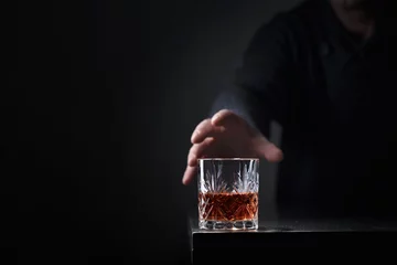 Foto op Plexiglas Bar Man& 39 s hand reikt naar een glas alcohol.