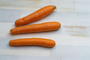 Three carrots on  wooden background, copy space
