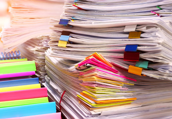 Close up pile of unfinished paperwork on office desk waiting to be managed. Stack of business paper. Report papers stacks. Business and finance concept.