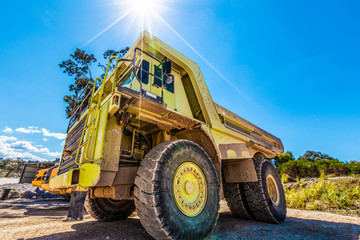 Enormous green dumper truck under sun flare