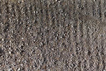 Dirt road with small stones and vertical grooves as a background