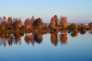 Autumn trees reflect the lake.