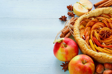 Autumn apple pie on the wooden board decorated with fresh apples, hazelnuts, spices - anise,...