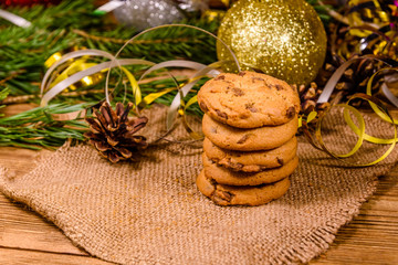 Stack of the chocolate chip cookies on sackcloth in front of christmas decorations