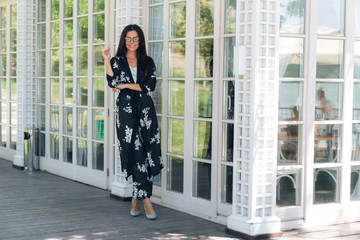 A stylish young woman in a silk suit came to the restaurant for an important meeting, wears fashionable clothes, stylish glasses, waits for her colleagues to discuss important issues at dinner.