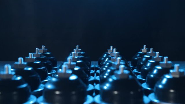 Industry mass production of products tilt-on 4K. Tilt down shot on a large number of rubber products in focus on the black background. Blue light shines from above.