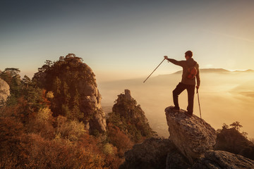 Hiker man standing on top of the mountain and looking at the beautiful valley from a height of at sunset.