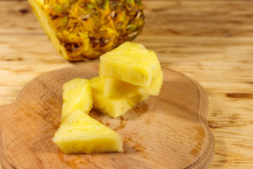 Pieces of pineapple on a cutting board on wooden table