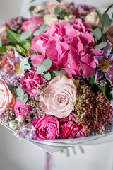 beautiful spring bouquet. Young girl holding a flowers arrangement with various of colors. white wall.
