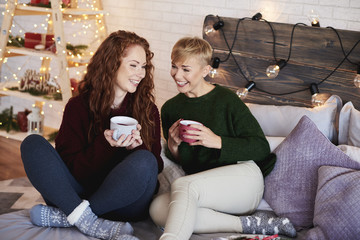 Friends drinking tea and talking at bedroom