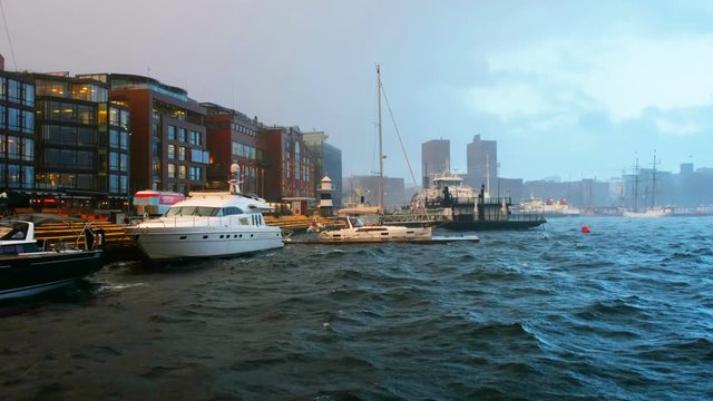 Oslo, Norway. Downtown Oslo, Norway, on a stormy evening, with moored boats and minimalistic scandinavian-style buildings on the background and storm waves