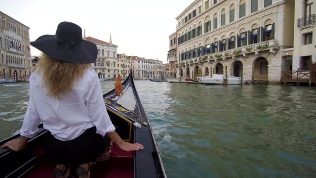 Woman in Venice on Gondole ride romance in boat on travel vacation holidays. Sailing in venetian canal in gondola. Italy.