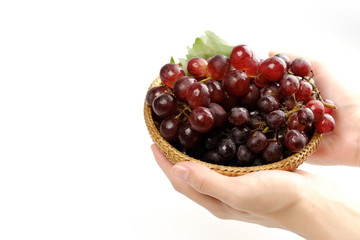 Hand holding a basket of fresh grapes.