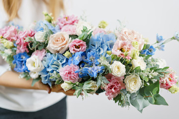 beautiful spring bouquet. Young girl holding a flowers arrangement with various of colors. white wall.