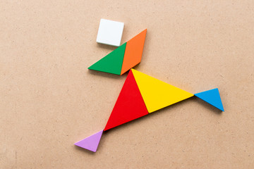 Color tangram puzzle in running or joy people shape on wood background