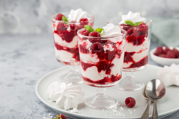 Eton mess, traditional english dessert, meringues, whipped cream, berry sauce and fresh raspberry in  glass