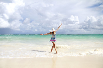 Young slim beautiful woman dancing  on the beach, playful, dancing, running, summer dream vacation, sunny, having fun, positive mood,  splashing water, happy 