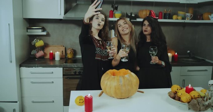 Selfie time at Halloween party , girls taking pictures smiling masked in a witch, background decorations for Halloween. 4k