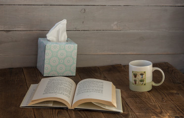 a cup with cafe an open book and a box with napkins
