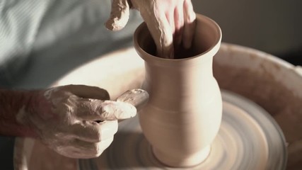 Artist operates hands, which gently creating correctly shaped handmade from clay. Traditional pottery making, teacher shows the basics of pottery in art studio