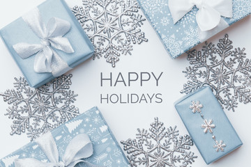 Beautiful christmas gifts and silver snowflakes isolated on white background. Pastel blue colored...