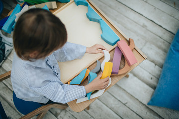 Fototapeta premium Little boy playing wooden puzzle game 