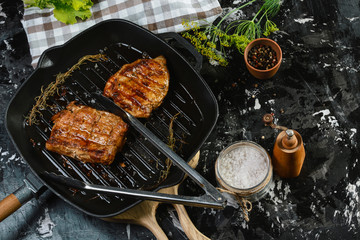 cooking rib eye steak with herbs on grill pan with rosemary and sea salt. Authentic lifestyle image. Top view. Copy space