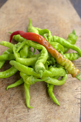 Capsicum annuum sweet chilli peppers, group of green fruits on wooden cutting board