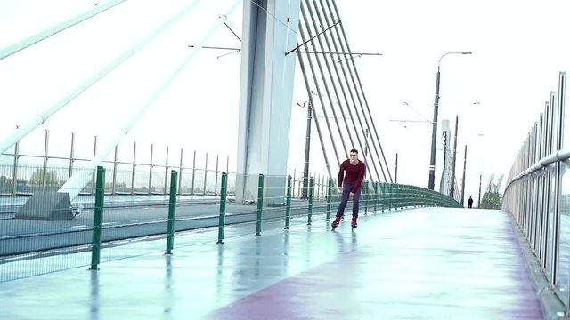 Portrait of handsome man in rollerblades riding in the city, super slow motion 
