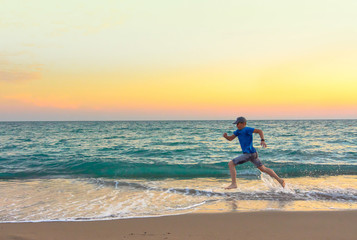 Boy running along the beach at sunset