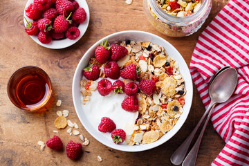 Healthy breakfast. Fresh granola, muesli with yogurt and berries on wooden background. Top view.