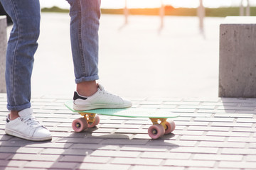 Beautiful teen female skater sitting on ramp at the skate park. Concept of summer urban activities